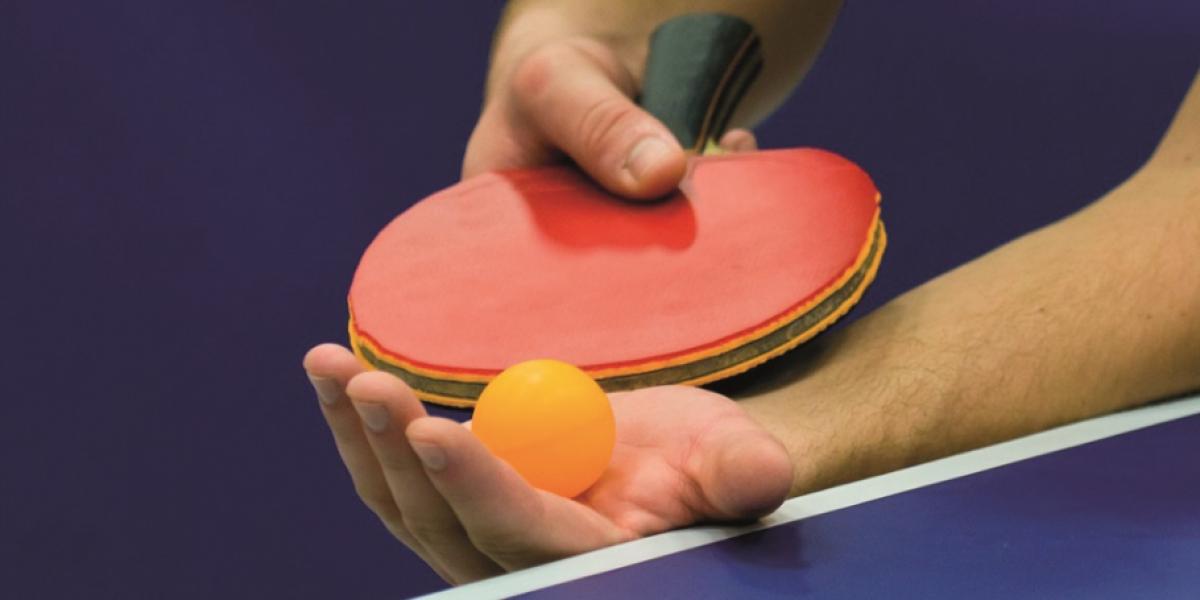table tennis bat and ball in players hand