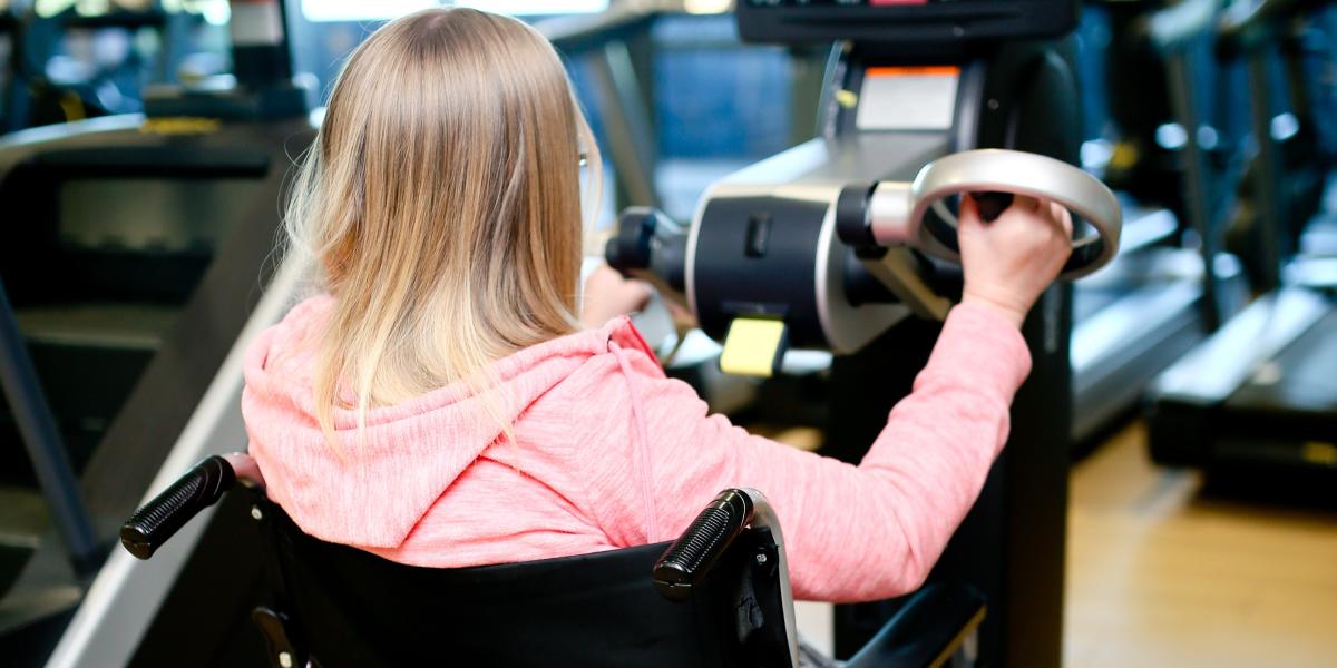 Wheel chair user on hand bike in the gym